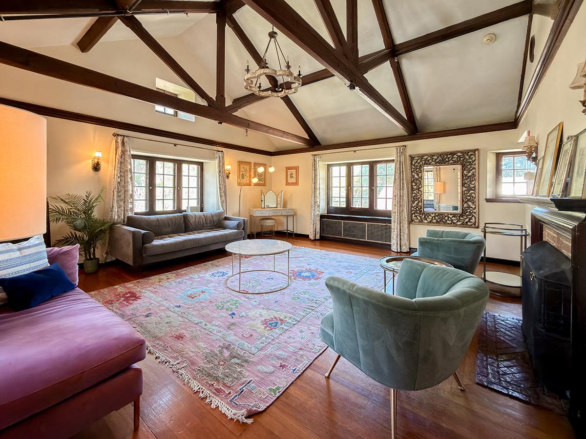 Spacious living room with wooden beams, colorful rug, and cozy seating.