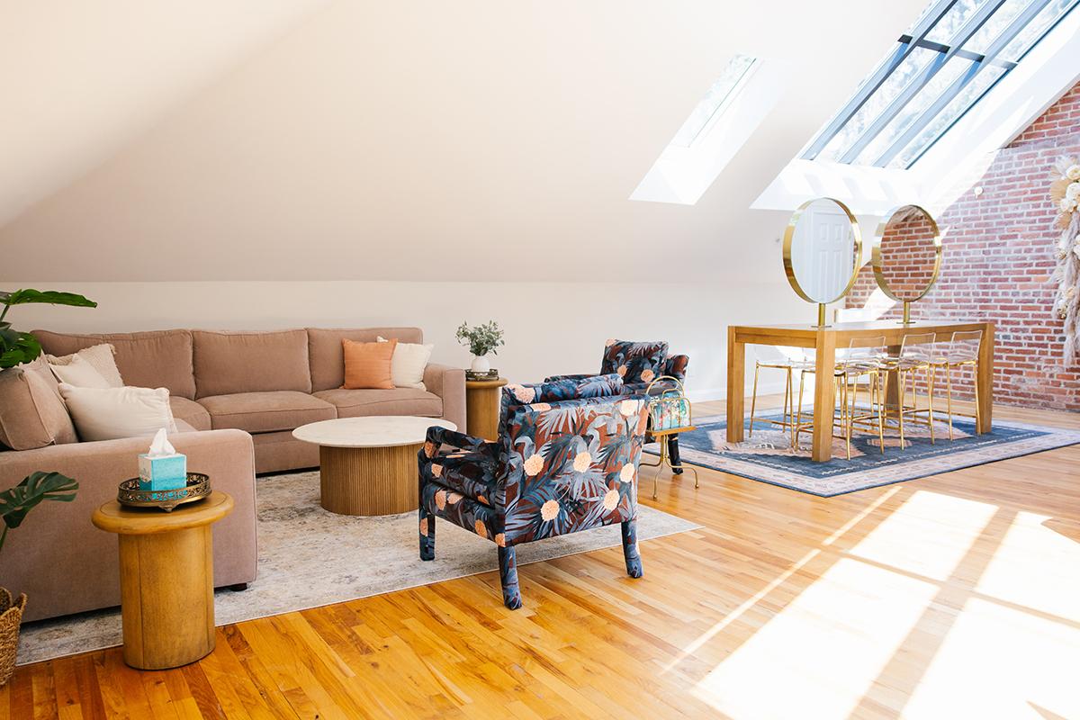 Cozy loft with a sofa, floral chairs, and skylights.