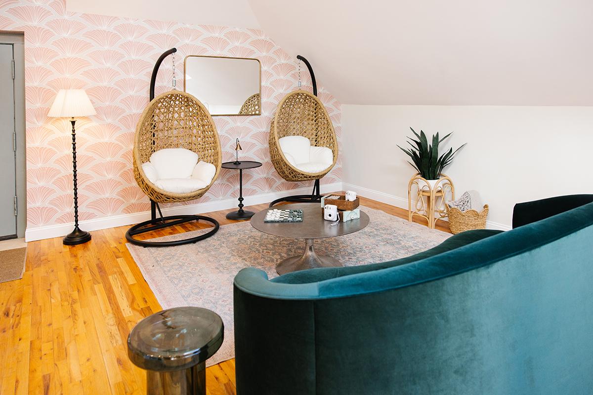 Cozy room with hanging chairs, teal sofa, and soft lighting.