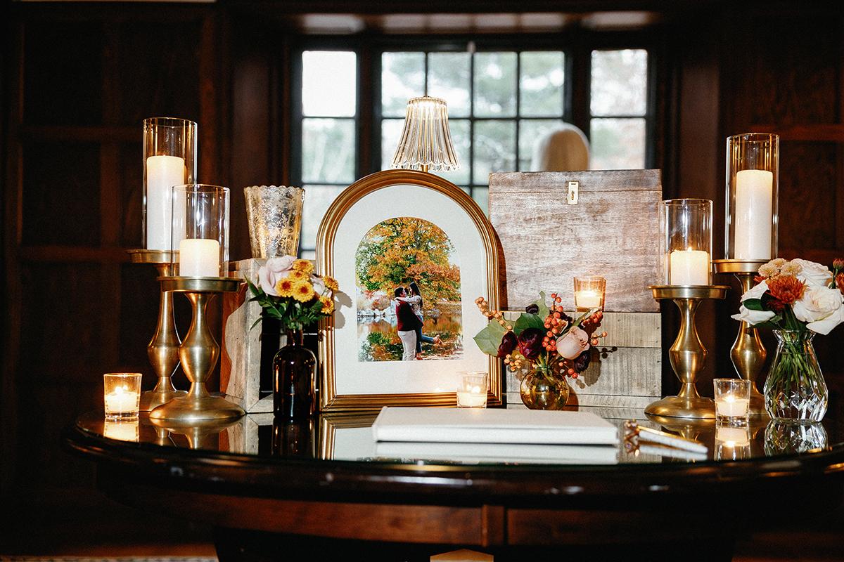 Candlelit table with flowers and framed artwork in a cozy room setting.