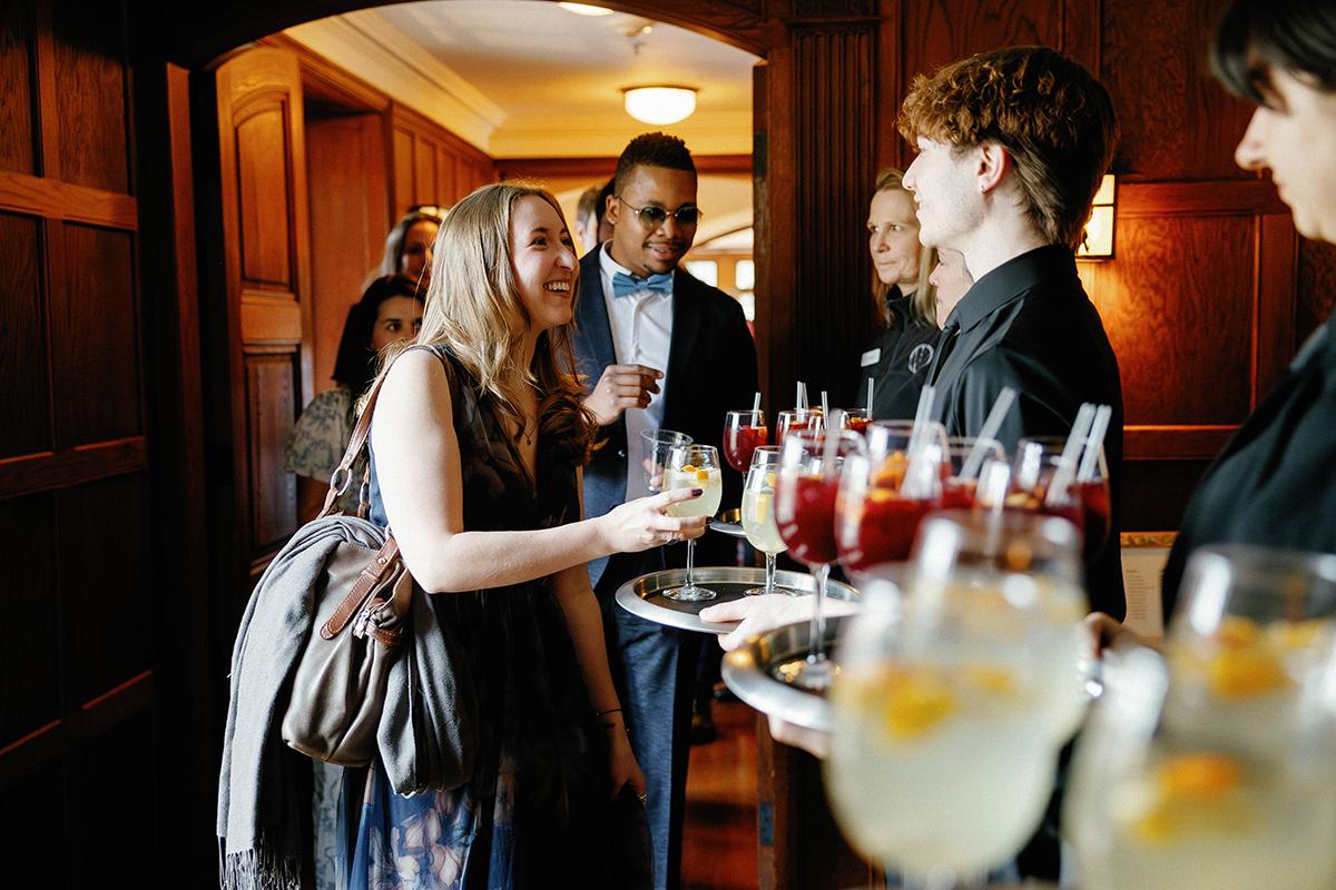 Cocktail servers offer drinks at a formal indoor event.