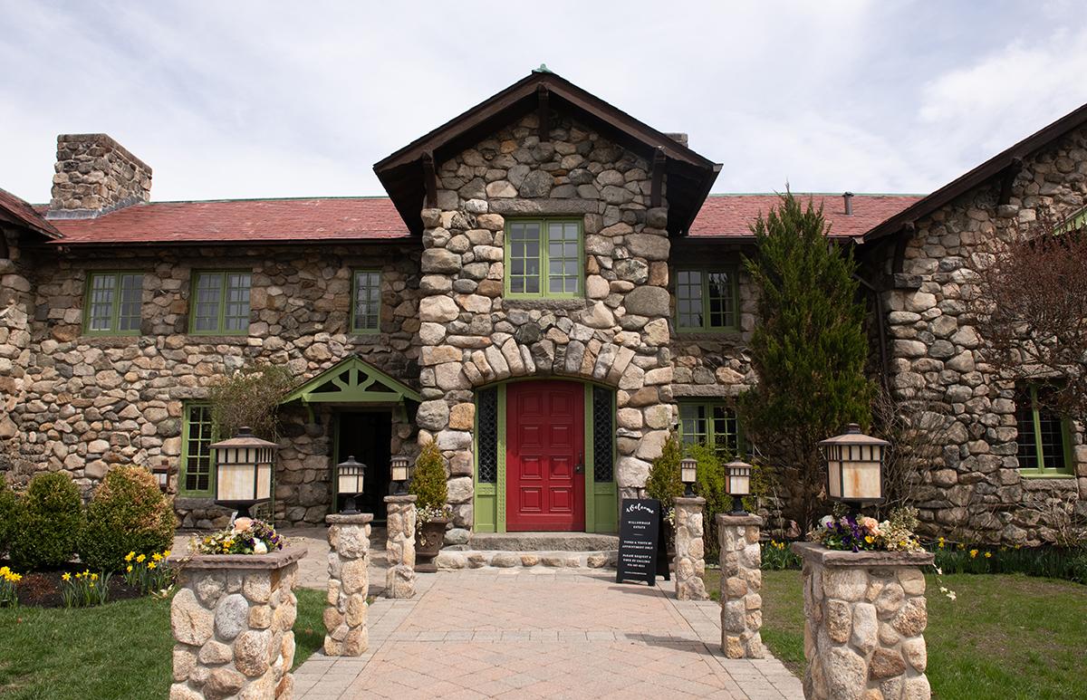 Stone building with red door, green windows, and landscaped path.