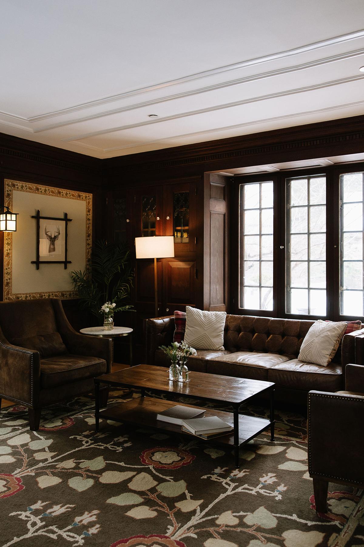 Elegant living room with brown sofas, large window, and patterned rug.