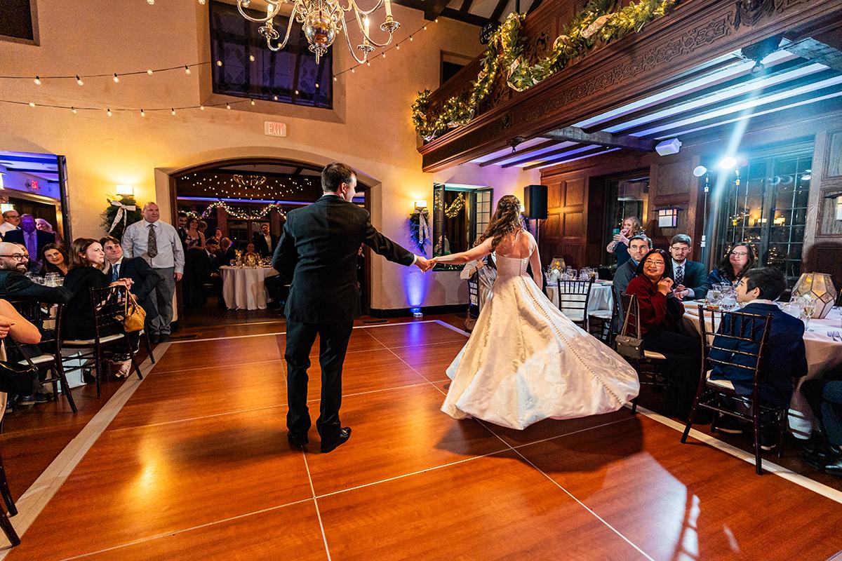 Bride and groom dancing in a warmly lit wedding reception hall.
