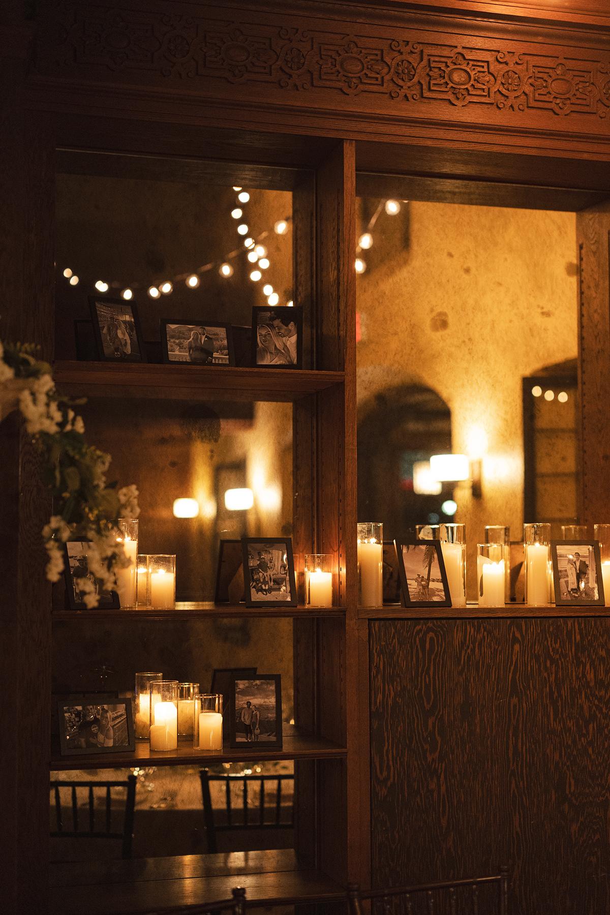 Candlelit display with string lights and framed photos on shelves.