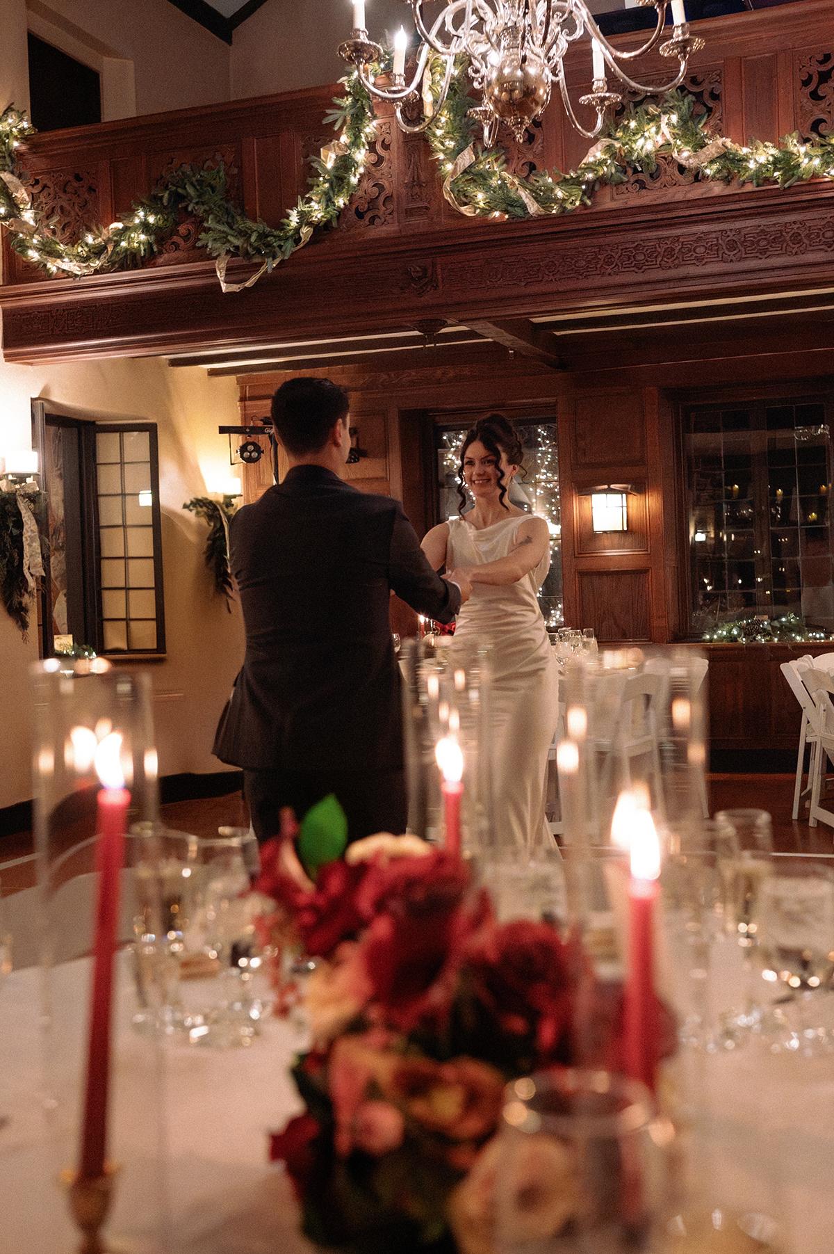 Elegant couple dancing in a warmly lit, decorated dining room.