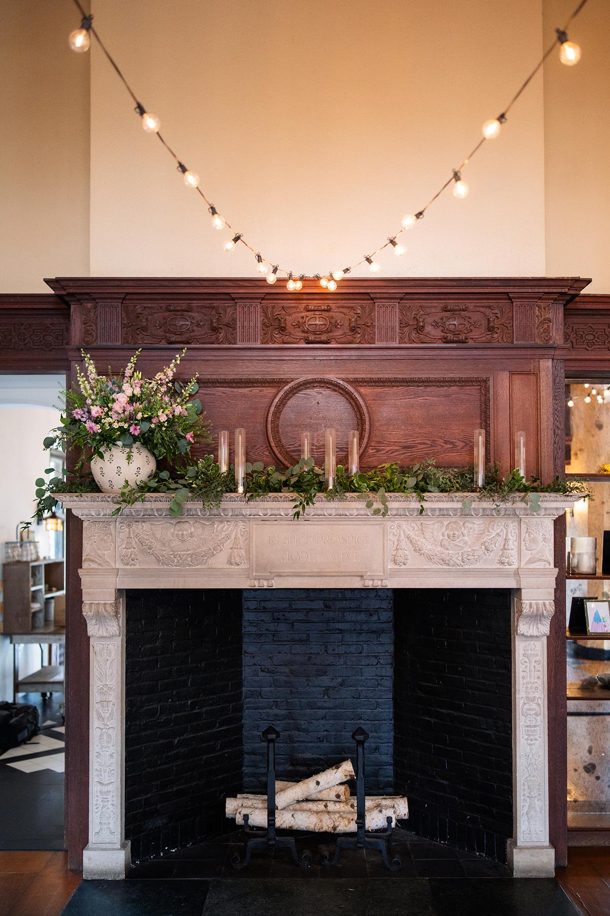 Elegant fireplace with candles, flowers, and string lights above.