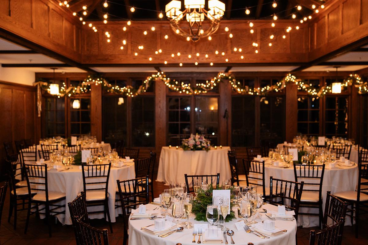 Cozy wedding reception with round tables and string lights.