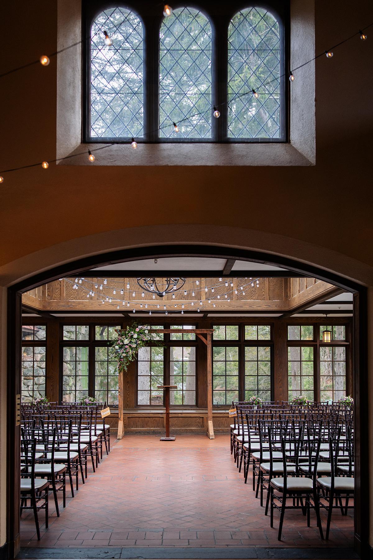 Arched hallway leads to an elegant wedding venue with chairs and floral decorations.