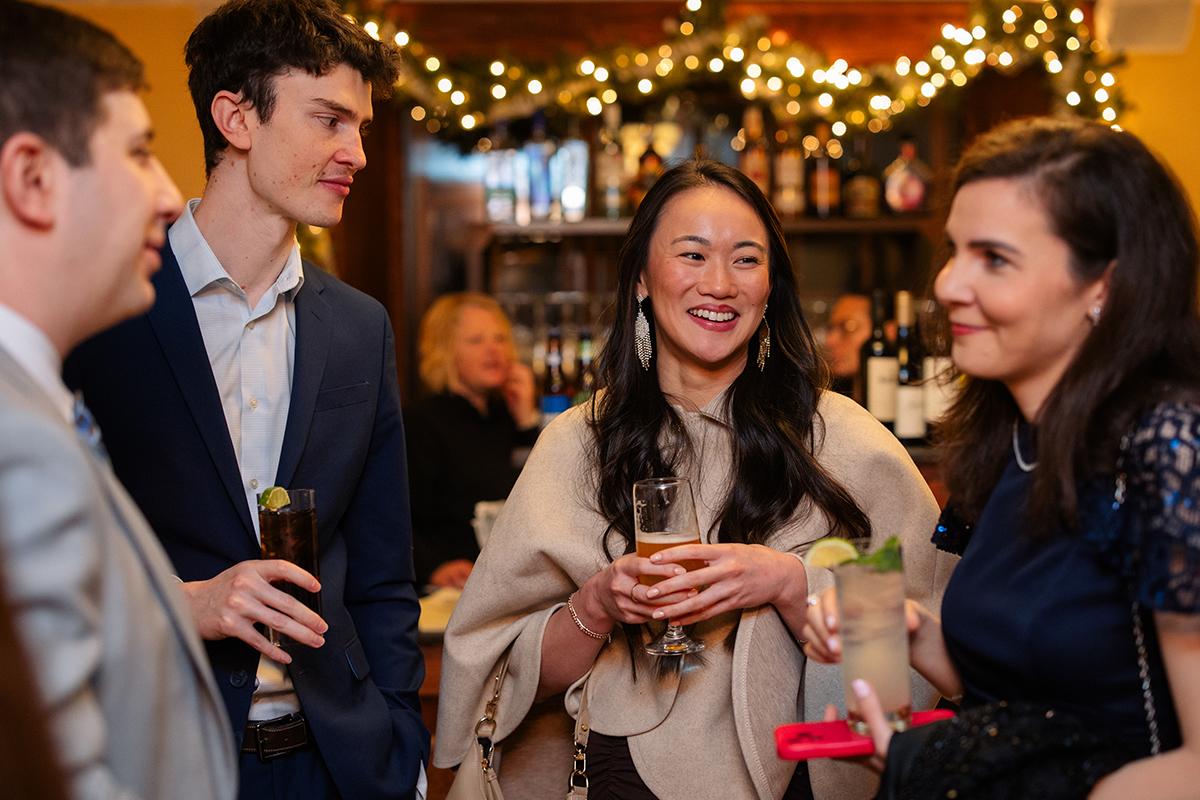 Group of people in formal attire smiling and chatting at a festive gathering.