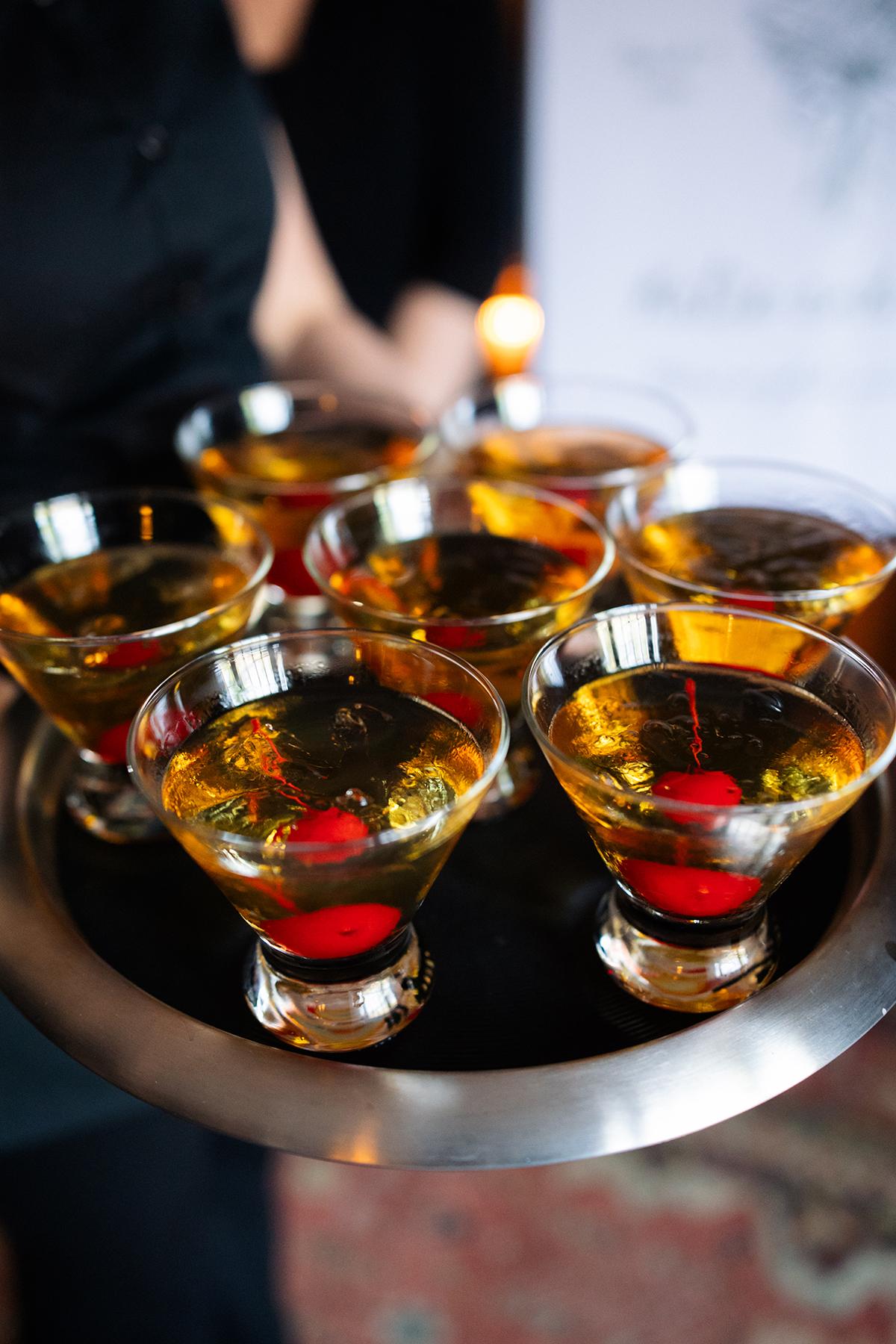 Cocktail glasses with cherries on a serving tray.
