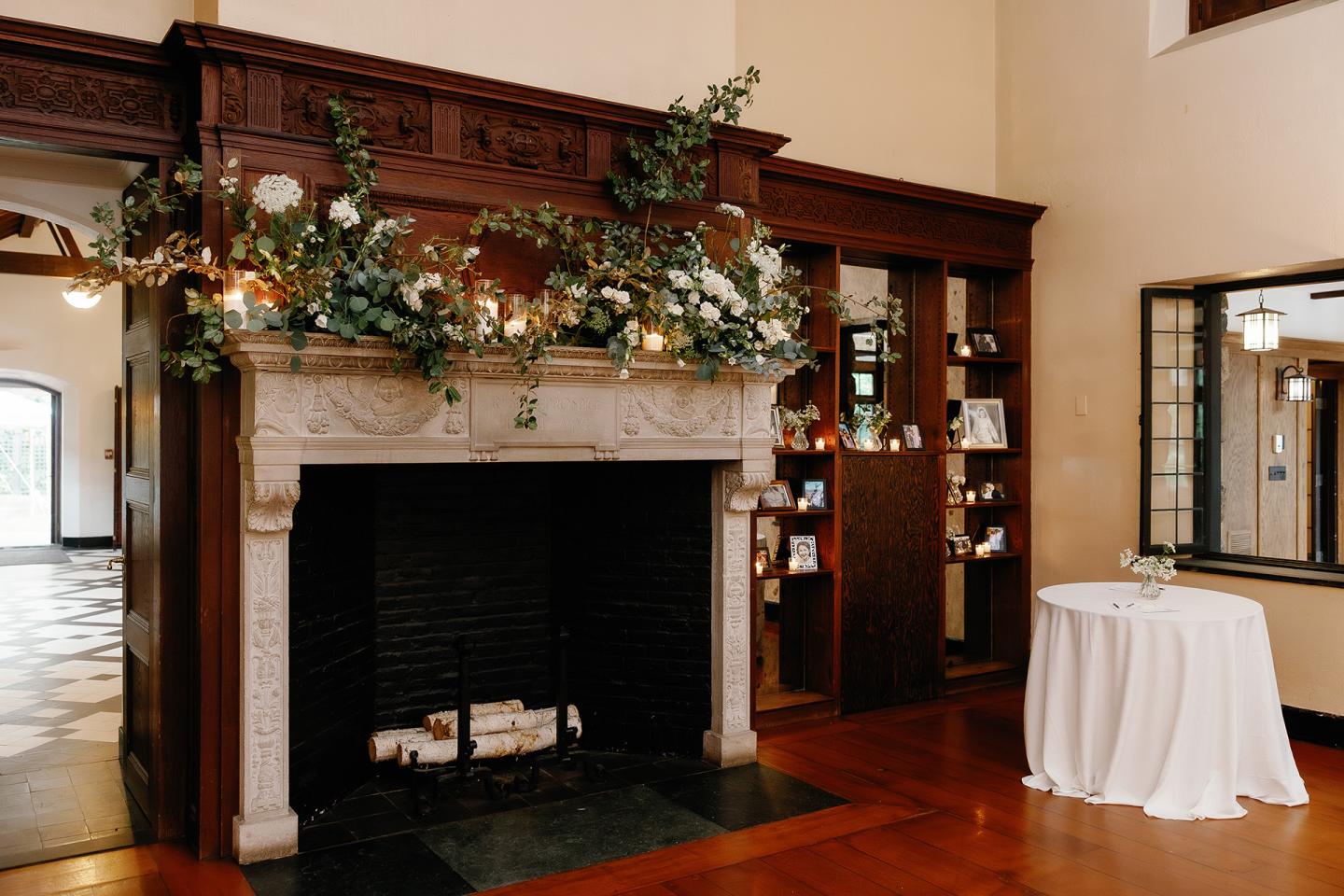 Elegant dining room fireplace decorated with garland and white flowers.